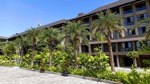 Un edificio moderno de varios pisos, rodeado de abundante vegetación y palmeras.