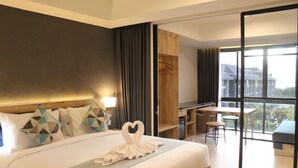Habitación de hotel con una cama grande, un escritorio y un balcón con vistas.