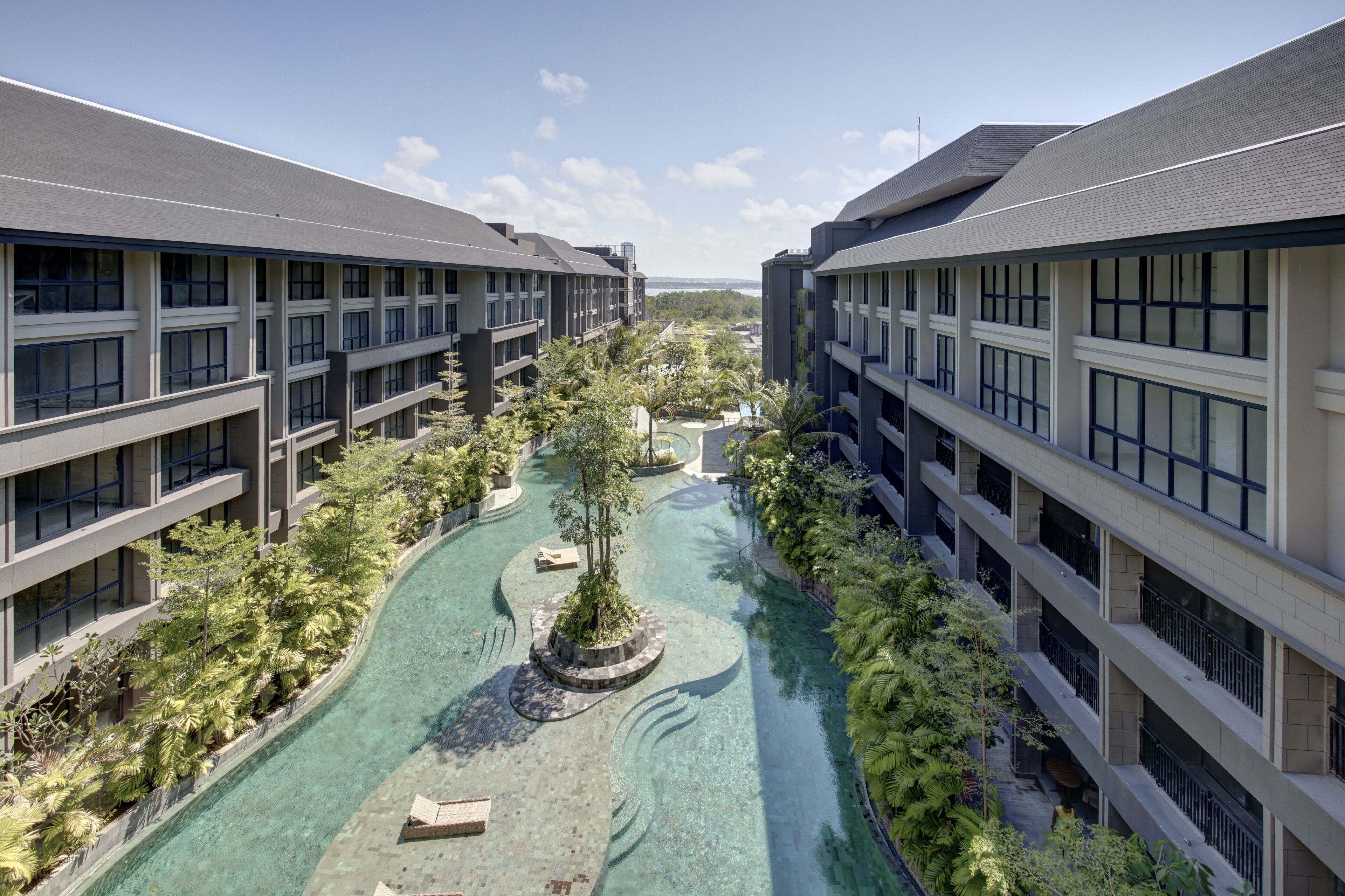 A modern hotel with a central courtyard featuring a clear water feature and lush greenery.