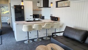 A modern kitchen with a central island, bar stools, a sofa, and a coffee table.