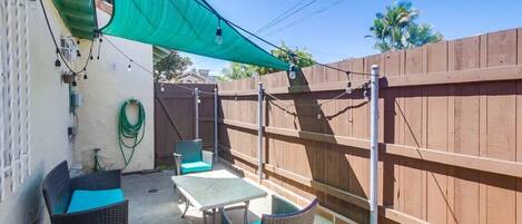 A patio with wicker furniture, a table, and a green shade sail.