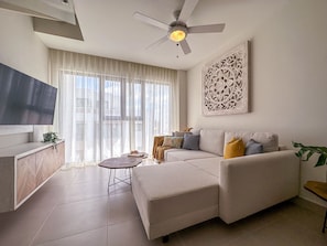 A modern living room with a sofa, a coffee table, and a TV. - Elegant and spacious Penthouse with Ocean View (Punta Cana)