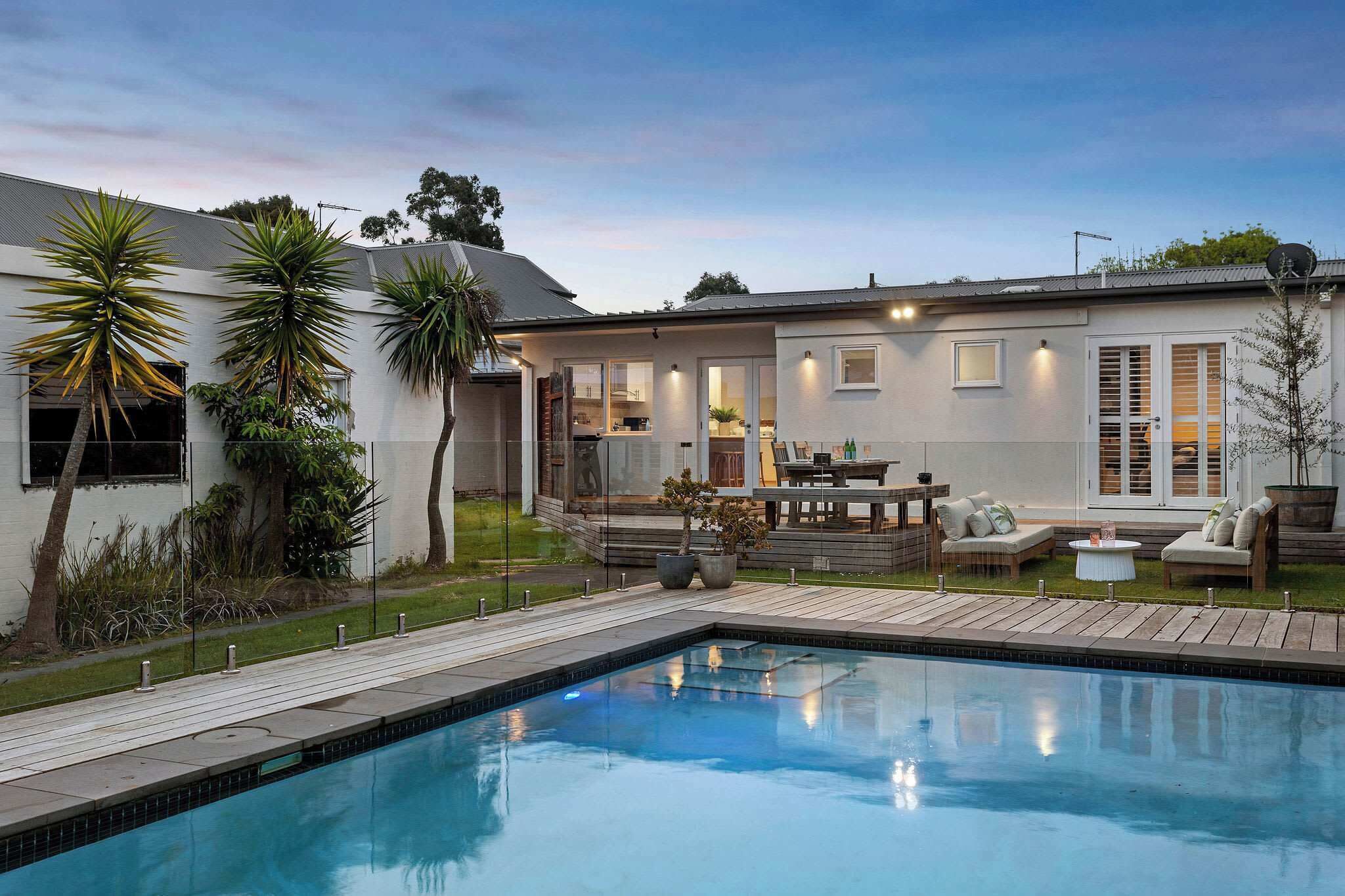 Une maison moderne dotée d’une piscine, d’un espace salon extérieur et d’un jardin bien entretenu.