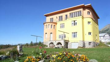 A two-story building with a curved facade, stone foundation, and a balcony on the upper floor.
