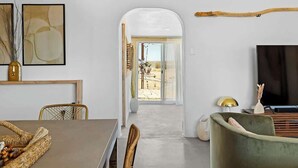 Un intérieur moderne comprenant un coin repas, un fauteuil vert et un téléviseur.