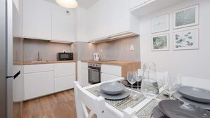 Een moderne keuken met witte kasten, een magnetron, en een eethoek met een tafel voor vier personen.