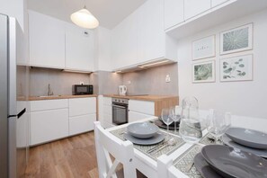 Une cuisine moderne avec des meubles blancs, un four à micro-ondes et un coin repas avec une table dressée pour quatre personnes.