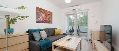 A modern living room with a sofa, coffee table, and a TV.