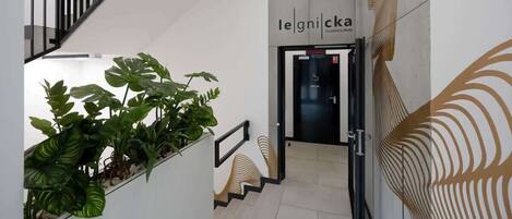Un interior moderno con una escalera, plantas en macetas y una puerta con la etiqueta 'legnicka'.