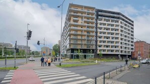 Een meerlaags gebouw met balkons, een voetgangersoversteek en een fiets op het trottoir.