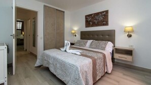 Ein Schlafzimmer mit Bett, Kleiderschrank, Nachttisch und einer Wandlampe.