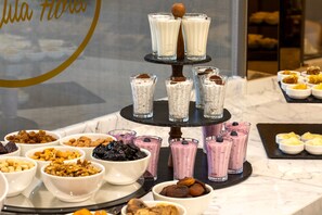 A dessert display with various bowls of nuts and a tiered stand holding glasses of smoothies. -  Me by Mula  (Istanbul)