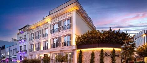 A multi-story hotel with a classic European architectural style, featuring balconies and a well-lit facade.