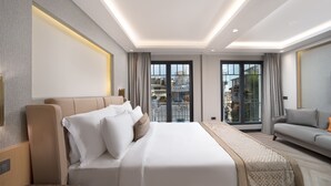 Una habitación de hotel moderna con una cama grande, un sofá y un balcón con vistas a la ciudad.