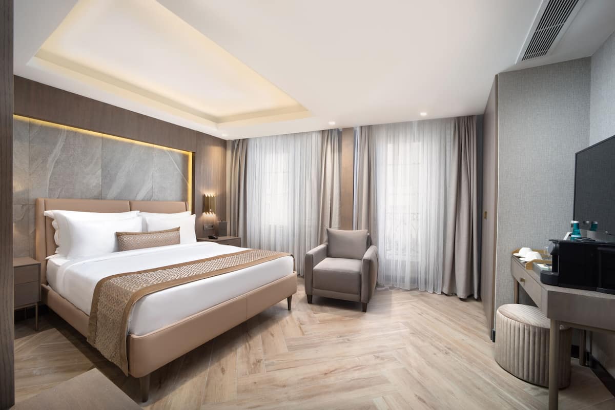 A modern hotel room with a large bed, a desk, and a chair.
