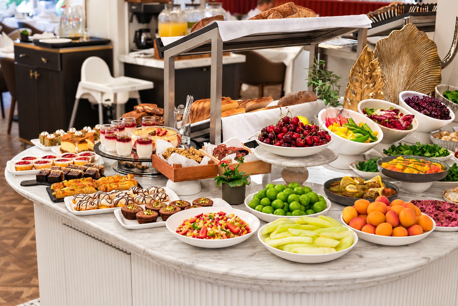A buffet with various food items including fruits, desserts, and bread.
