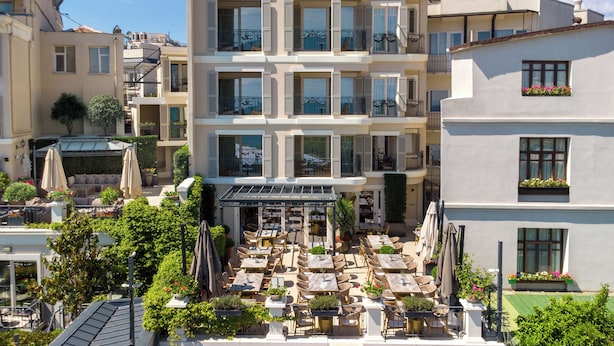 Terraza en la azotea con mobiliario exterior, una zona cubierta y vistas de edificios cercanos.