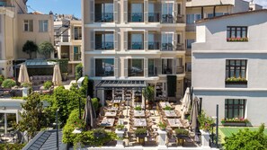 A rooftop terrace with outdoor seating, a covered area, and a view of adjacent buildings. -  Me by Mula  (Istanbul)