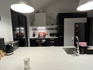 Enjoy cooking in this well-equipped kitchen with a stainless steel sink, compact microwave, and ample lighting.