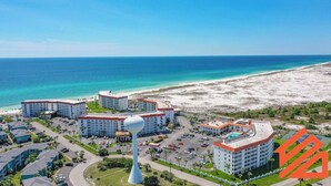 Ein Resort mit mehreren Gebäuden, einem Parkplatz und einem Strand.