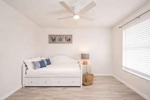 A bedroom with a white bed, a ceiling fan, a bedside lamp, and a window with blinds. - Dog-Friendly • Pool & Boat Dock • Sombrero Beach (Marathon)