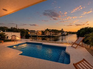 A swimming pool with a view of a water body and houses in the background. - Dog-Friendly • Pool & Boat Dock • Sombrero Beach (Marathon)