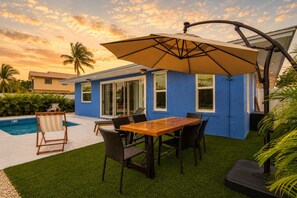 A patio area with a pool, a table with chairs, and a large umbrella. - Dog-Friendly • Pool & Boat Dock • Sombrero Beach (Marathon)