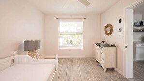 A bedroom with a bed, a bedside lamp, a dresser, a mirror, and a window with blinds. - Dog-Friendly • Pool & Boat Dock • Sombrero Beach (Marathon)