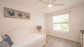 A bedroom with a bed, a ceiling fan, a window with blinds, and wall-mounted artwork. - Dog-Friendly • Pool & Boat Dock • Sombrero Beach (Marathon)