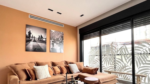 A modern living room with a sectional sofa, a marble coffee table, and artwork on the wall. - Jerusalem 9 - By Beach Apartments TLV (Bat Yam)