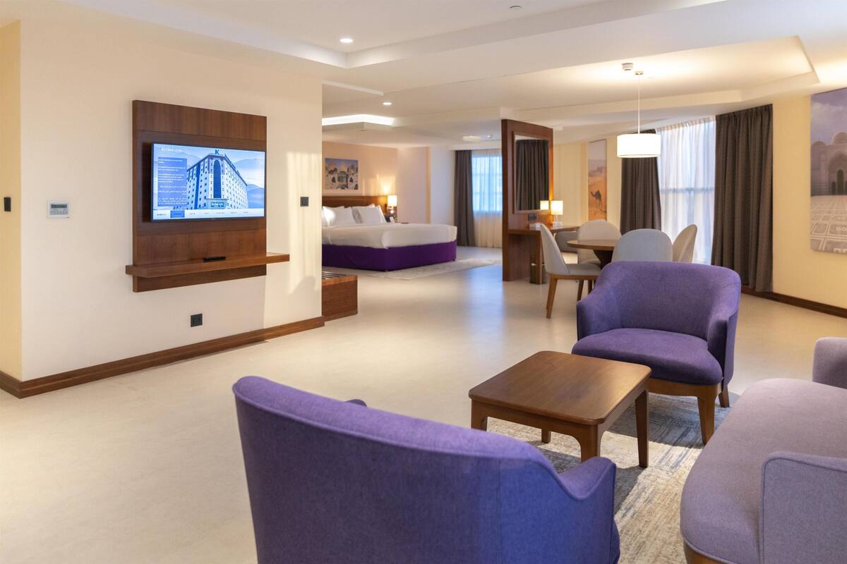 Een hotelkamer met een bed, een bureau, een stoel, een televisie en een bank.