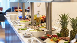 Een buffet met diverse gerechten en een televisie op de achtergrond.
