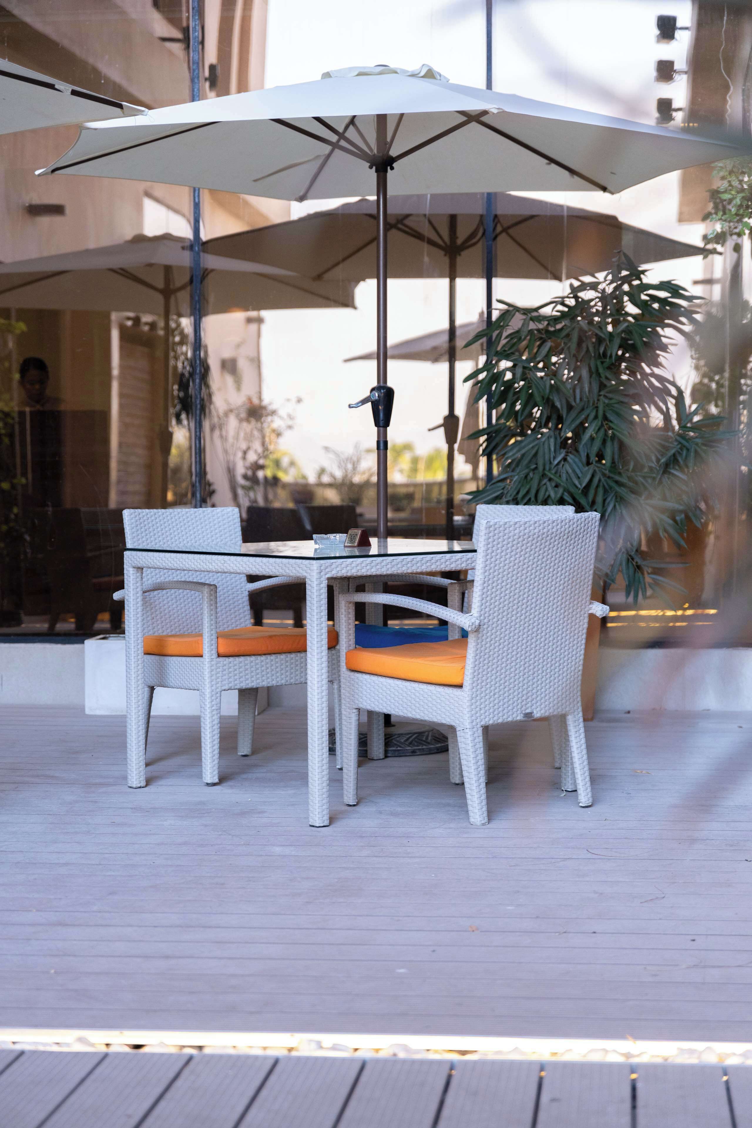 An outdoor patio with a table and chairs, an umbrella, and a potted plant.