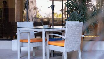 Un patio al aire libre con una mesa, sillas, un paraguas y una planta en maceta.