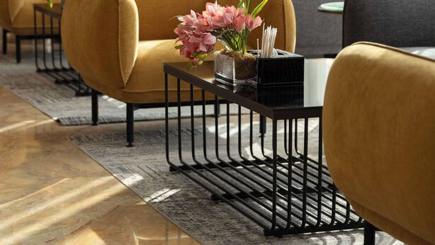 Een moderne hotellobby met een bank, fauteuils en een salontafel.