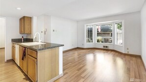 Une cuisine spacieuse avec un îlot central en bois, des meubles blancs et une grande fenêtre qui laisse entrer la lumière naturelle.