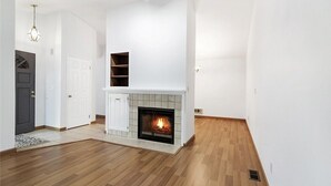 Un salon moderne avec une cheminée, un plancher en bois et des murs blancs.