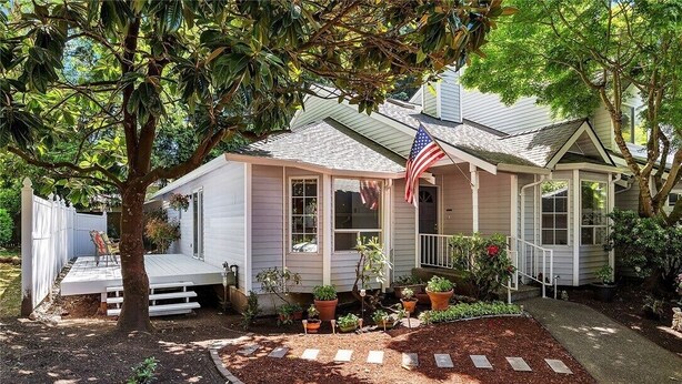 Une maison de plain-pied avec un porche, un drapeau américain et un jardin agrémenté d’un chemin de pierres.