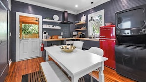 Una cocina moderna con una mesa blanca, un refrigerador rojo y un horno negro.