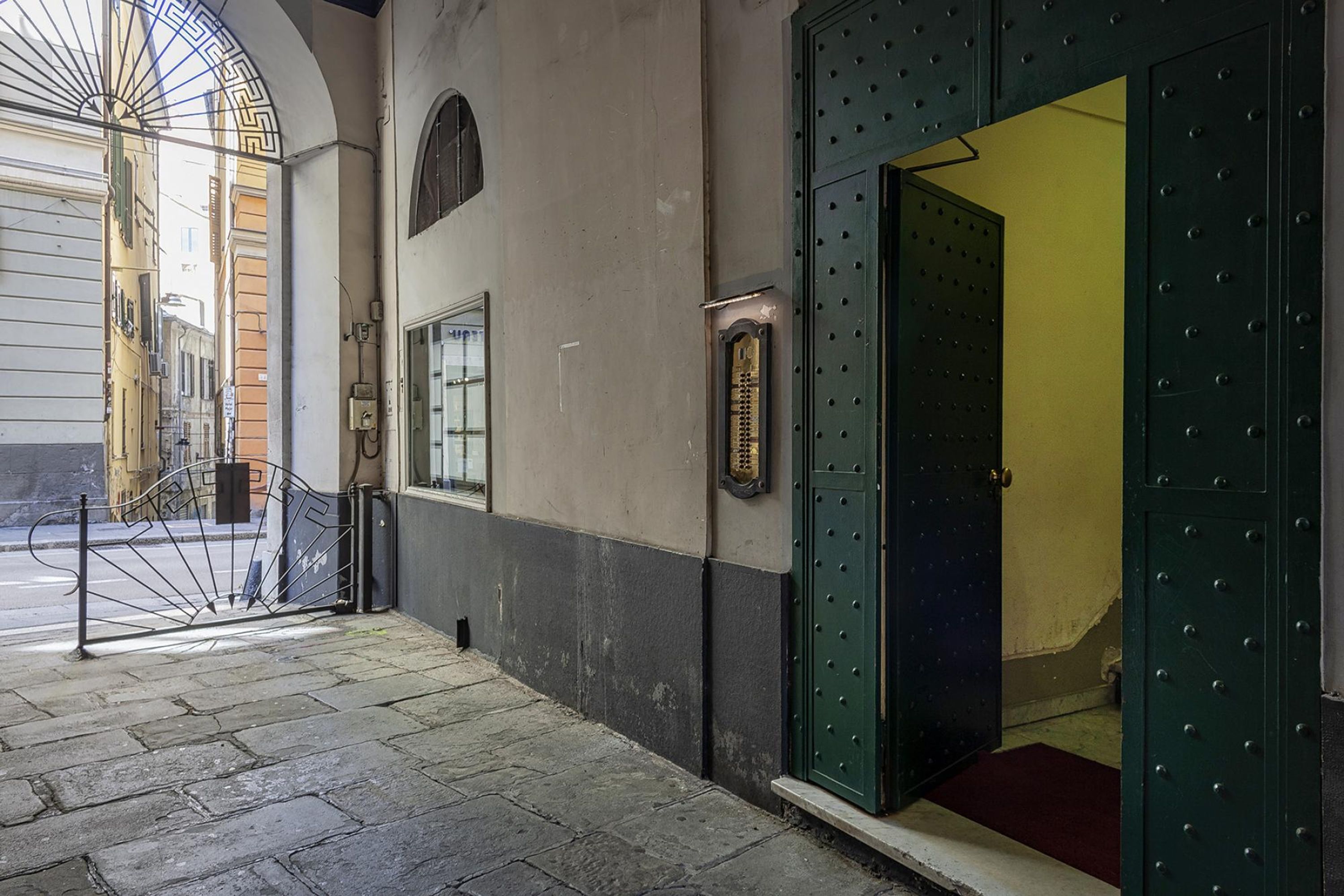 A narrow street with a metal gate and a green door leading to a building.
