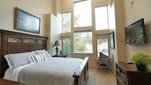 A bedroom with a large bed, a television, a chair, and a window with a view of the outside. - Stunning Panoramic Views of Mtns & Lake (Eden)
