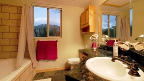 A bathroom with a bathtub, toilet, sink, and windows with a view of mountains. - Stunning Panoramic Views of Mtns & Lake (Eden)