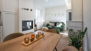 Una sala de estar moderna con un sofá verde, una mesa de comedor de madera con velas y una chimenea.