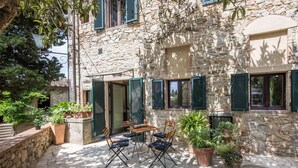 Un edificio de piedra con un patio, mesas al aire libre y plantas en macetas.