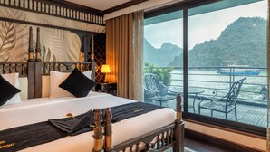 Camera d'albergo con un letto grande, vista su un corpo d'acqua e un balcone con mobili da esterno.