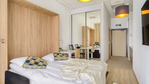 Une chambre d’hôtel moderne équipée d’un lit, d’un bureau et d’une armoire.