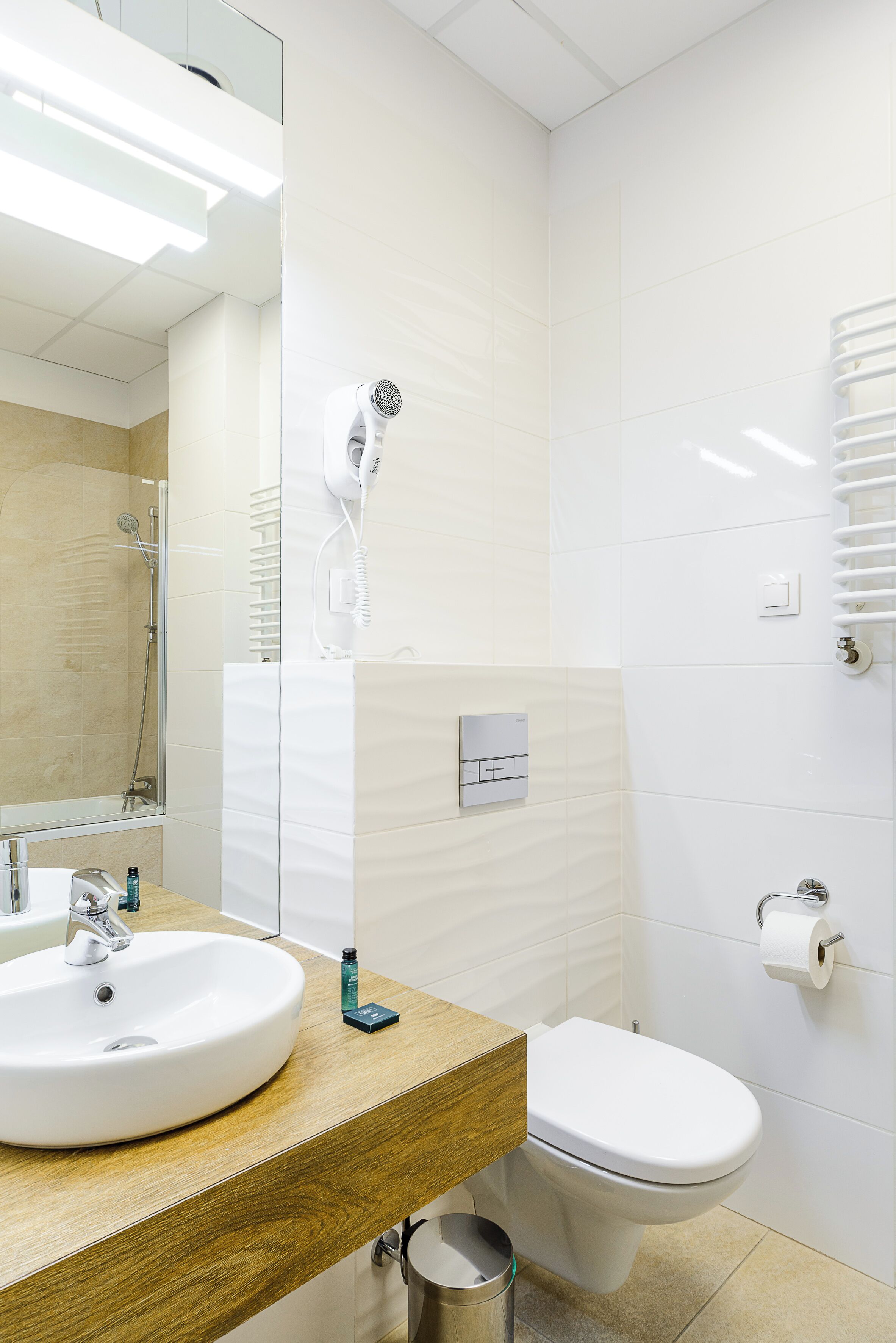 A modern bathroom with a sink, toilet, and a hairdryer mounted on the wall.