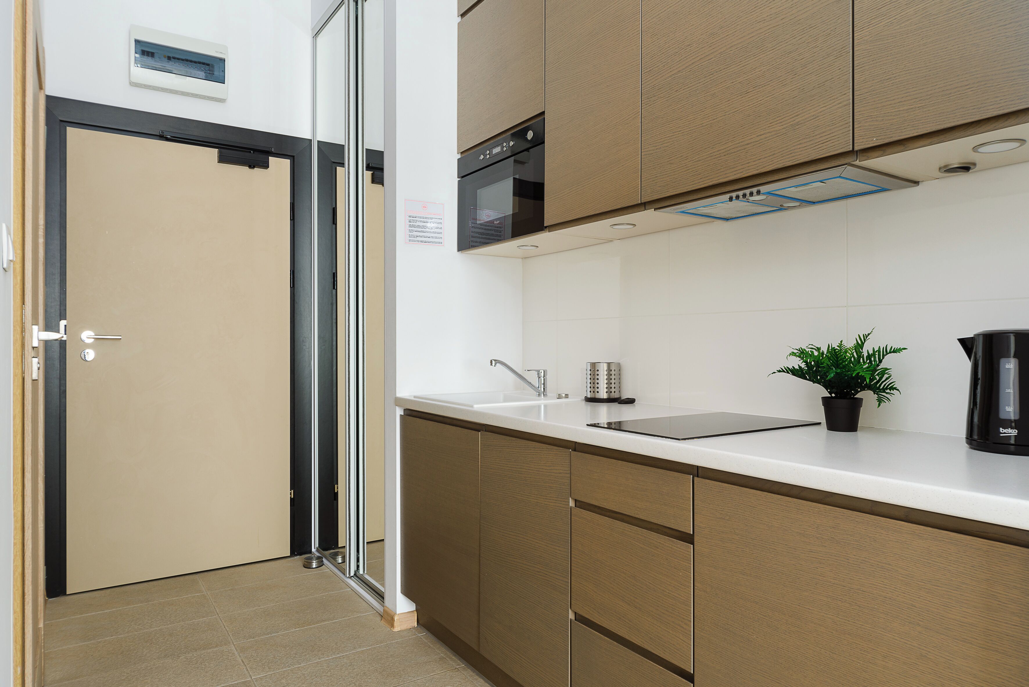 A modern kitchen with wooden cabinets, a stainless steel sink, and a black coffee maker.