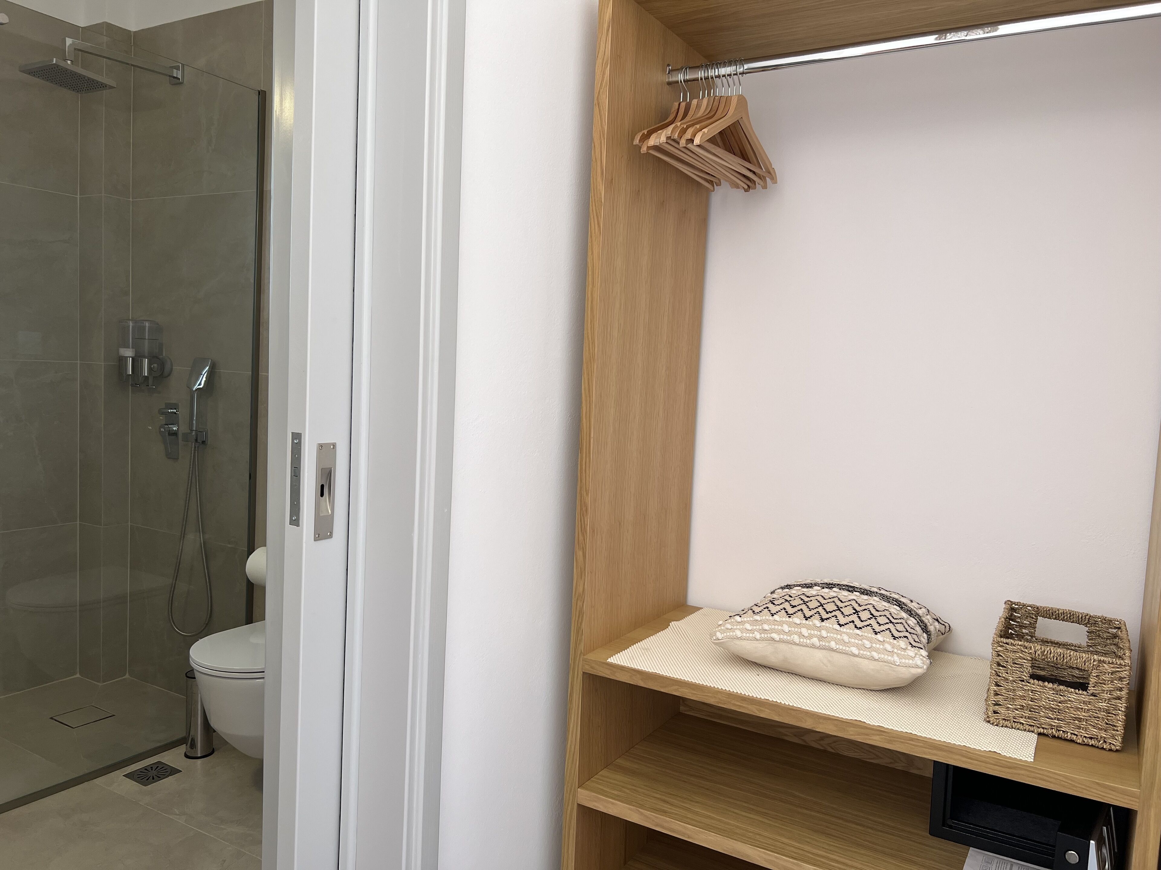 Un baño moderno con cabina de ducha de vidrio, inodoro y tocador de madera con estante.