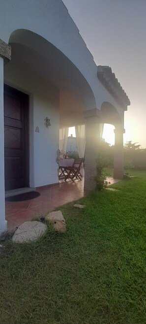 A house with a covered porch, a door, and a small table with chairs. - Apartment I Gelsomini # (Tanaunella)